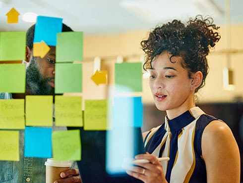 girl standing in front of a clear board with post-it notes