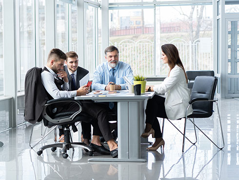 four people sitting at a table in a meeting